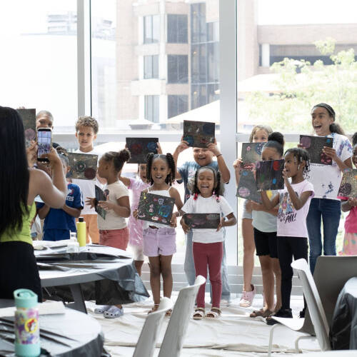 Jamari Taylor takes a cell phone photo of young artists holding up their artwork in the Battle Creek Innovation Hub